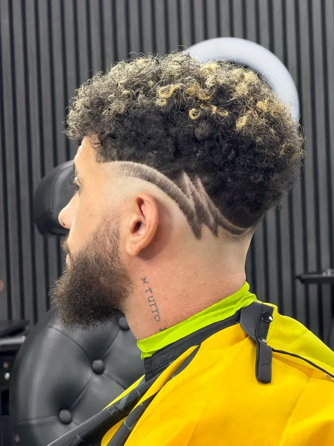 Blonde curly crop with a hard part and a beard fade