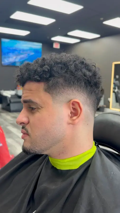 Curly top over a mid fade, side profile